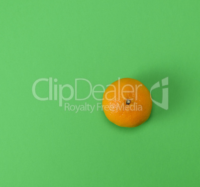 one ripe orange tangerine peel on a green background