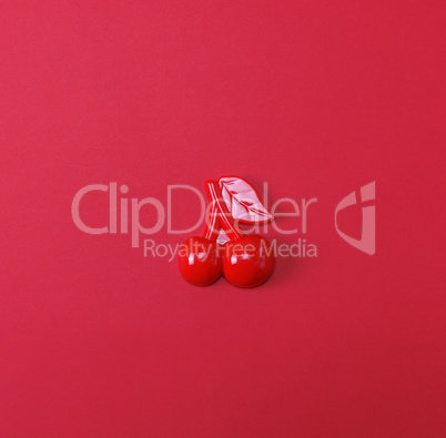 Red plastic childrens toy cherry on a red background