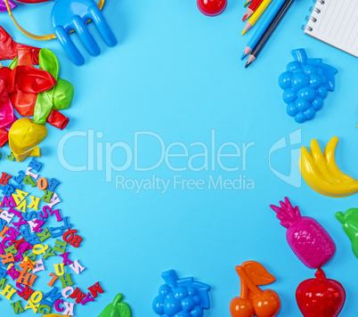 Blue background with childrens plastic toys, pencils, balloons a