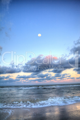 Moonset over the ocean at Vanderbilt Beach at sunset