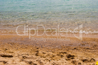 A small wave of blue sea on a sandy beach