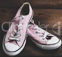 pair of old worn pink sneakers with white laces