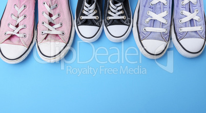 three pairs of textile worn shoes on a blue background