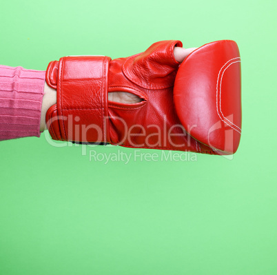 hand is wearing a red leather boxing glove on a green backgroun