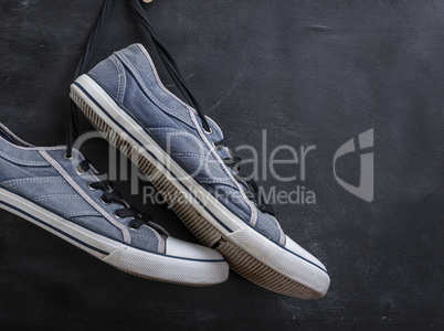 pair of textile blue sneakers hang on a string
