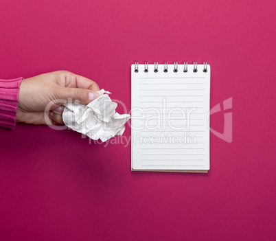 female hand holding a white crumpled sheet of paper