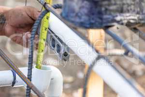 Plumber Using Level And Tape Measure While Installing PVC Pipe