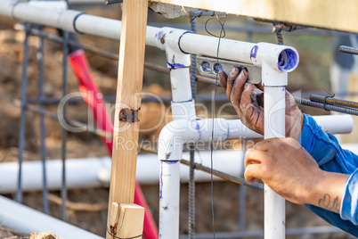 Plumber Using Level While Installing PVC Pipe At Construction Si