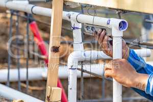 Plumber Using Level While Installing PVC Pipe At Construction Si