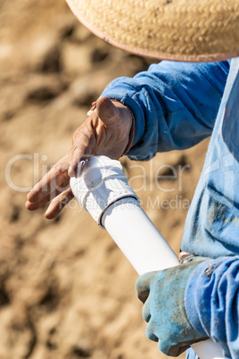 Plumber Applying Glue To PVC Pipe At Construction Site