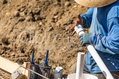 Plumber Applying Glue To PVC Pipe At Construction Site