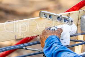 Plumber Using Level While Installing PVC Pipe At Construction