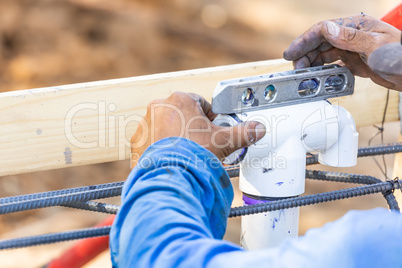 Plumber Using Level While Installing PVC Pipe At Construction Site