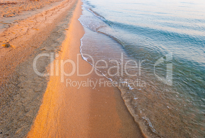 Beautiful deserted sandy beach with small waves of surf