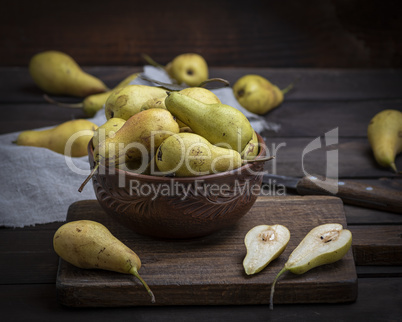 ripe green pears in a brown clay bowl on a table