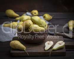 ripe green pears in a brown clay bowl on a table