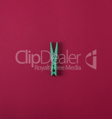 Green plastic clothes pin on a red background