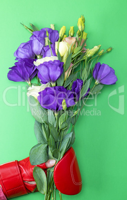 hand in a red boxing glove holding a bouquet of flowers