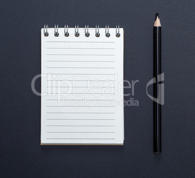 notebook with white sheets in line and black wooden pencil