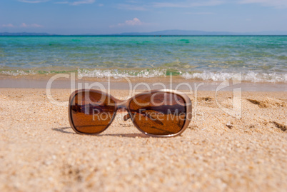 Sunglasses on the beach near the sea against the sea wave