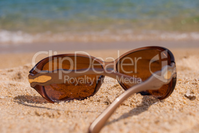 Sunglasses on the beach near the sea against the sea wave