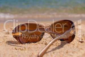 Sunglasses on the beach near the sea against the sea wave