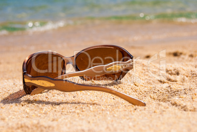 Sunglasses on the beach near the sea against the sea wave