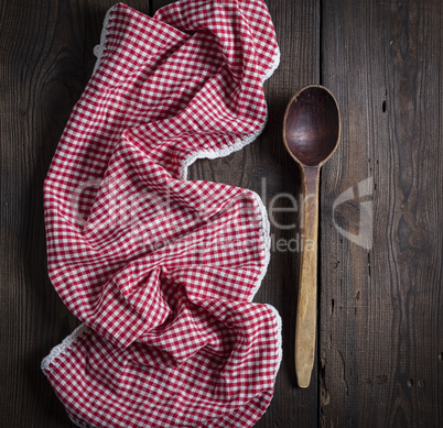 very old empty wooden spoon and red kitchen towel on a brown woo