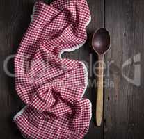 very old empty wooden spoon and red kitchen towel on a brown woo