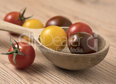 Cherry tomatoes in a variety of colors in wooden spoon.
