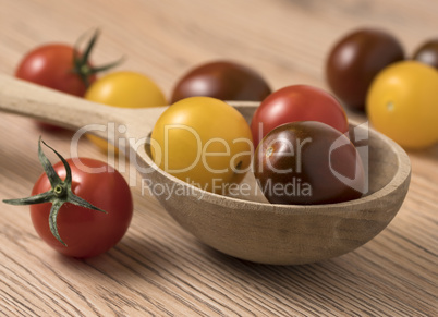 Cherry tomatoes in a variety of colors in wooden spoon.