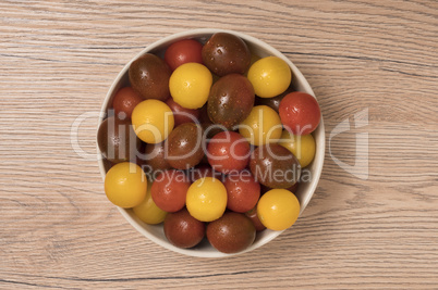 Cherry tomatoes, red,yellow and kamato in ceramic bowl on wooden