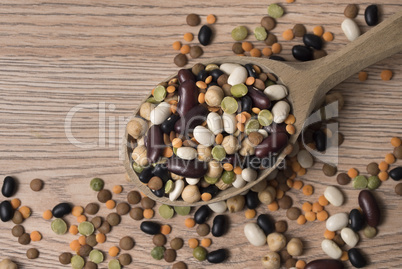 Legumes of various kinds in a wooden spoon on the table.