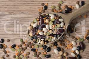 Legumes of various kinds in a wooden spoon on the table.