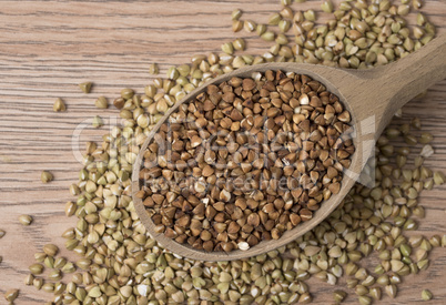 Natural fresh buckwheat in wooden spoon. On a wooden table.