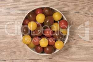 Cherry tomatoes, red,yellow and kamato in ceramic bowl on wooden