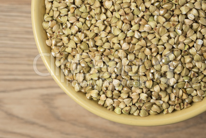 Natural fresh green buckwheat in ceramic bowl on wooden backgrou
