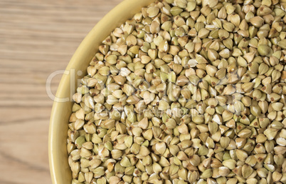 Natural fresh green buckwheat in ceramic bowl on wooden backgrou