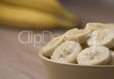 Sliced banana in ceramic bowl on wooden background. Close up.