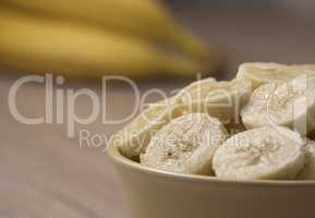 Sliced banana in ceramic bowl on wooden background. Close up.