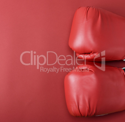 pair of red leather boxing gloves on a red background,