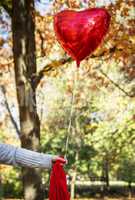 female hand holding a red balloon