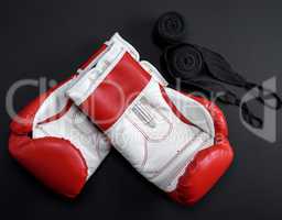 pair of red leather boxing gloves and a black textile bandage