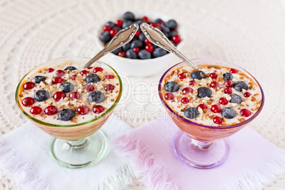 Two yogurt dessert with berries, almonds and spoons