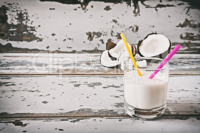 Coconut milk in a glass and a broken coconut on background