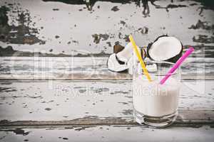 Coconut milk in a glass and a broken coconut on background