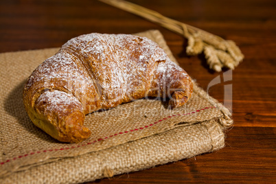 Croissant on a burlap and ears of wheat