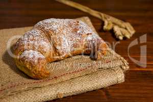 Croissant on a burlap and ears of wheat