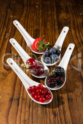 Collection of wild berries on white spoons