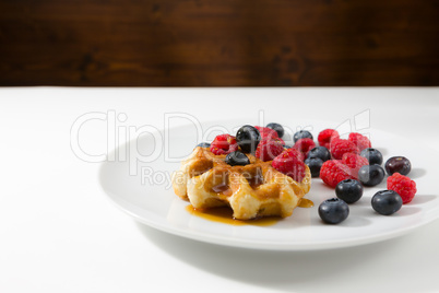 Waffles with fresh ripe berries over a white plate